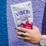 Hand holding packet of ViBERi Organic Blackcurrant Powder